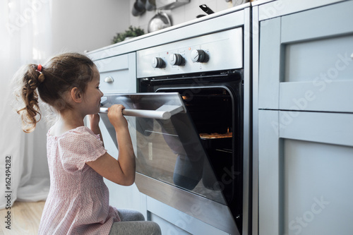 Girl looking into oven photo