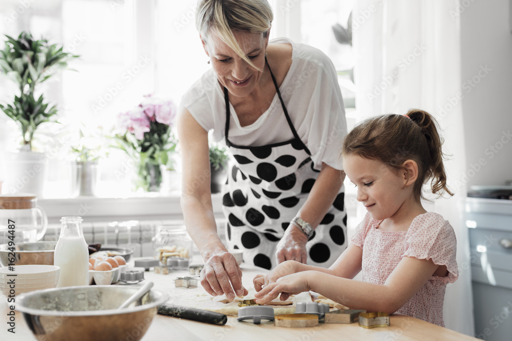 Cute little Caucasian girl enjoying making pastry with her mother at kitchen at home. Cute little Caucasian girl enjoying making pastry with her mother at kitchen at home.