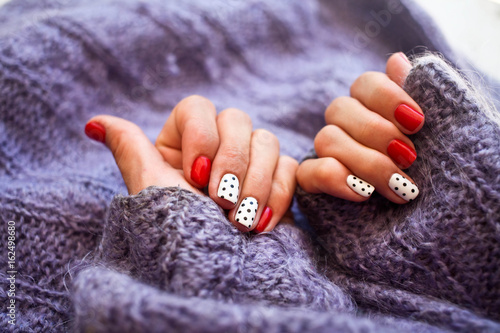 Woman hands with beautiful winter trend knit sweater manicure