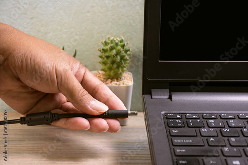 Hands of the mechanic who was to plug the power into the notebook.