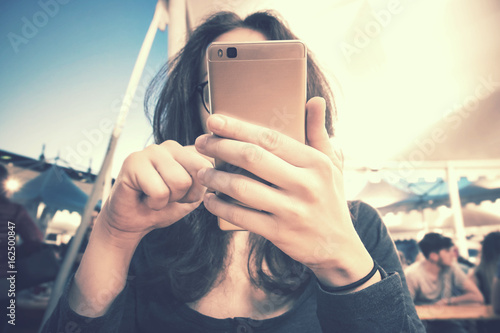 girl at fair with smartphone, lonely girl using cell, background with defocused people