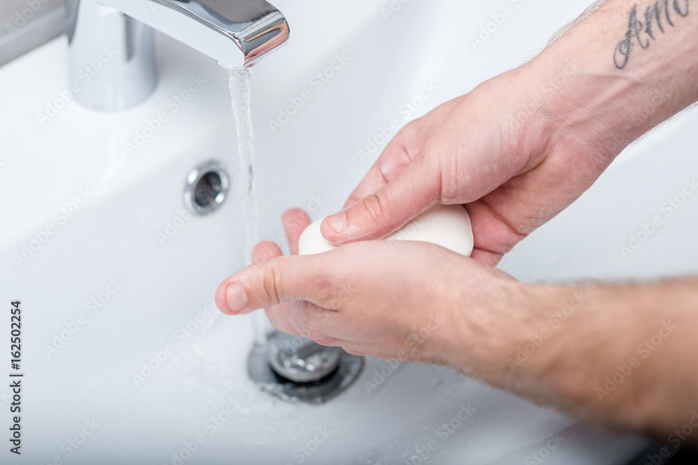 partial view of man washing hands with soup in morning partial view of man washing hands with soup in morning