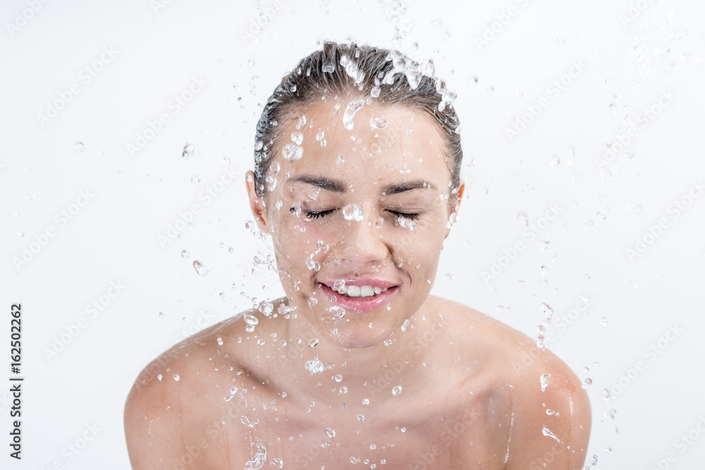 Portrait of smiling woman taking shower isolated on white