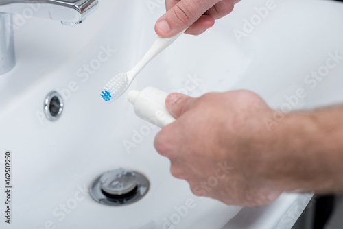 cropped shot of man applying toothpaste on toothbrush in bathroom © LIGHTFIELD STUDIOS