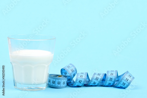 Glass of milk next to roll of blue measuring tape