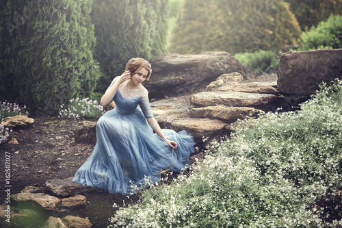 Fotografia Piękna młoda dziewczyna, taka jak Kopciuszek, chodzi po ogrodzie.