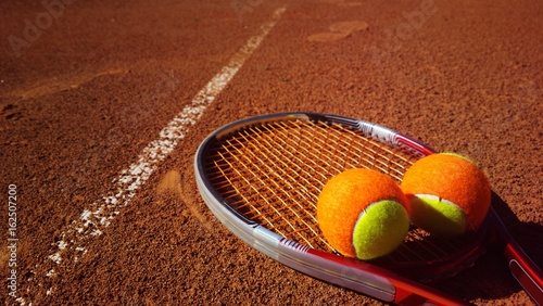 Tennisschläger mit Tennisbällen auf einem Tennisplatz © pattilabelle