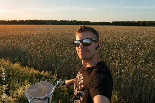 A young man makes a selfie while riding a bike,