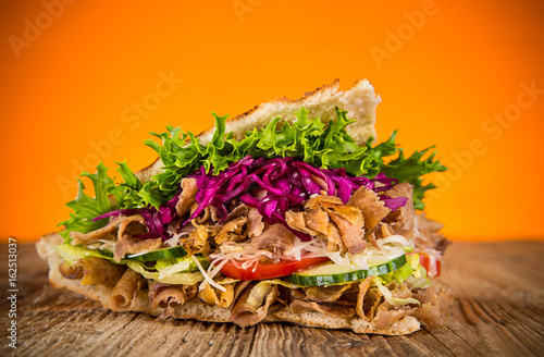 Close up of kebab sandwich on old wooden table.