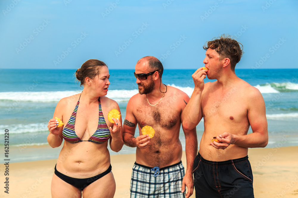 Two men and a girl are eating pineapple. Two men and a girl are eating pineapple.