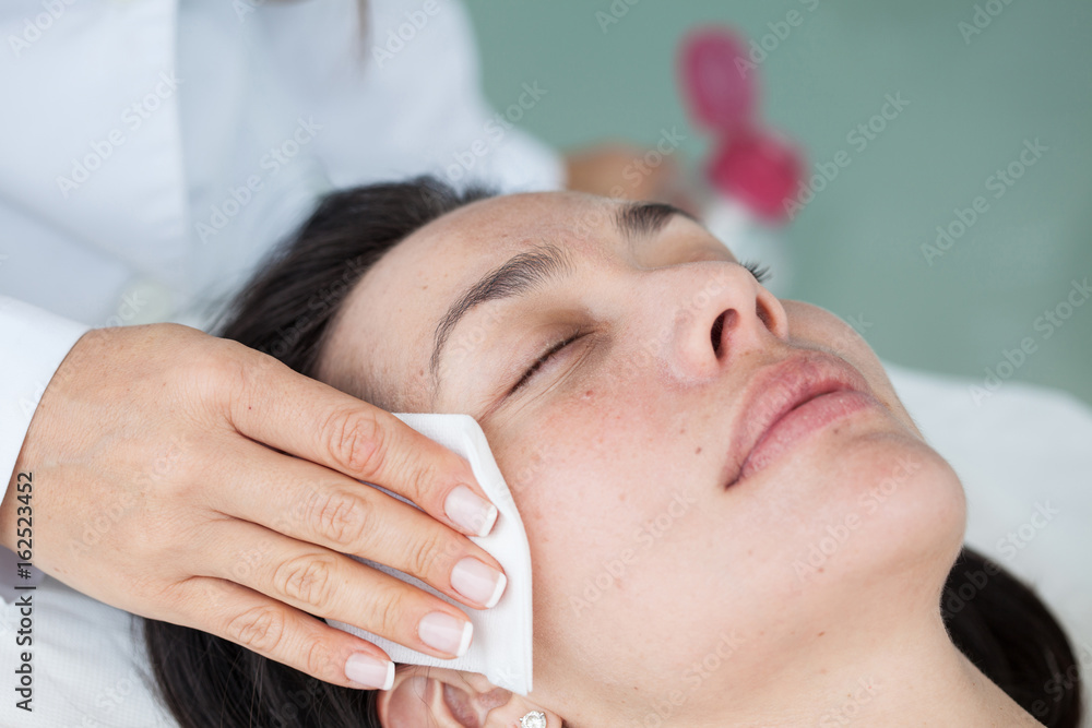 Doctor cleaning a woman patient face Doctor cleaning a woman patient face