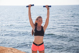 girl Sports Fitness with dumbbells on the beach