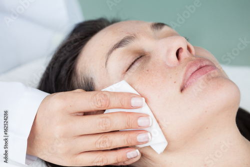 Doctor cleaning a woman patient face