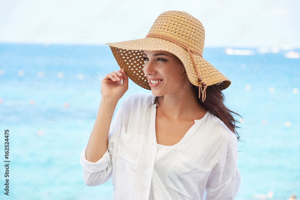 Young beautiful woman in a straw hat resting by the sea