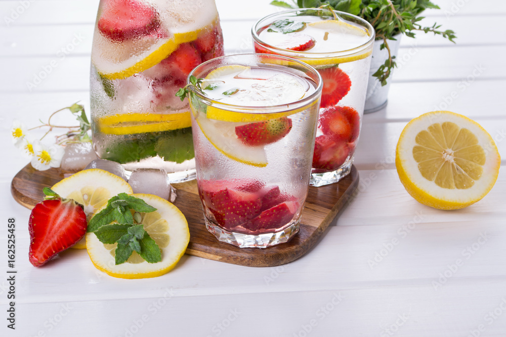 Mineral infused water with strawberry, ice, herb and mint leaves on white background, homemade detox soda water recipe. Mineral infused water with strawberry, ice, herb and mint leaves on white background, homemade detox soda water recipe.