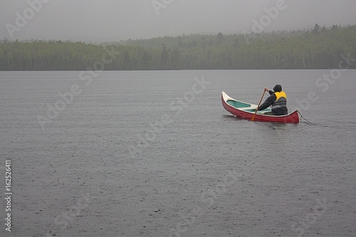 Canoeist paddling on a rainy day.