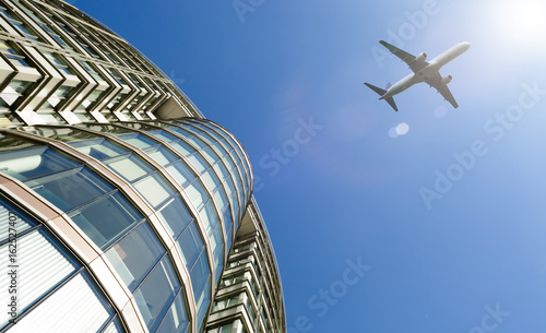 Plane flying above modern office building.