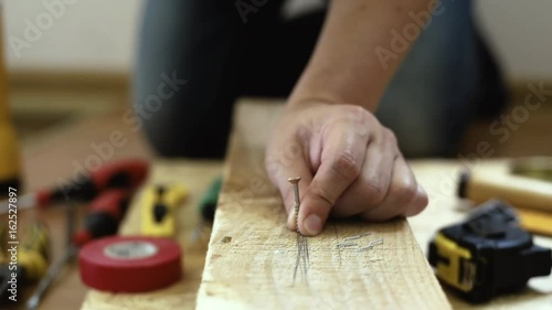 Craftsman hammering nail into wooden plank in studio.