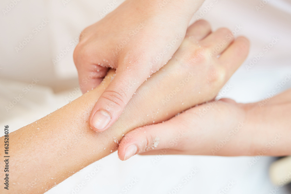 Woman Getting a Salt Scrub Beauty Treatment on hands in the Health Spa Woman Getting a Salt Scrub Beauty Treatment on hands in the Health Spa