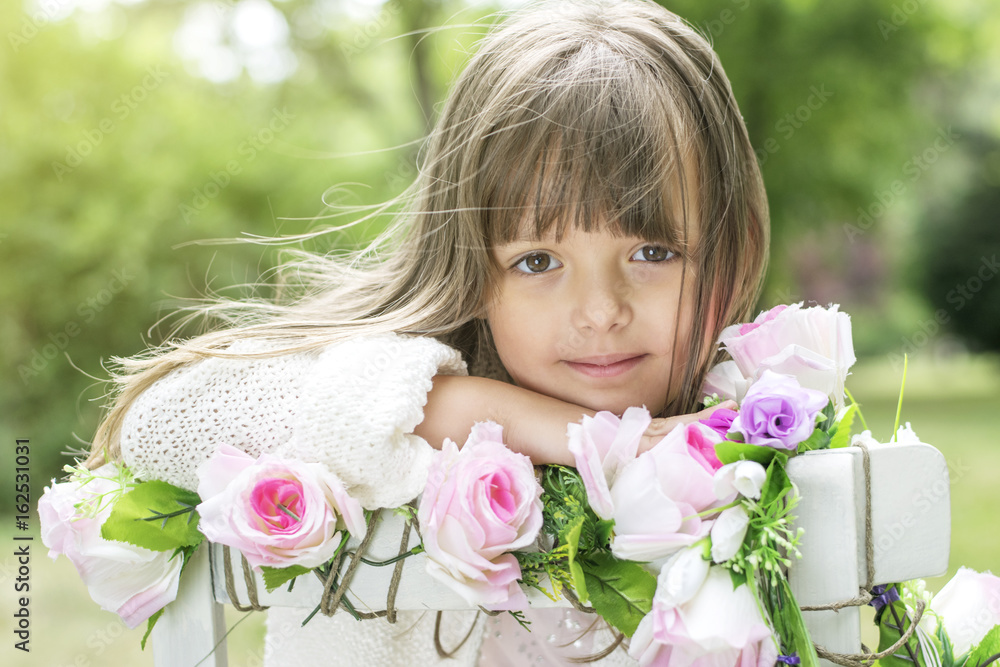 Fototapeta premium Cute kid girl posing with flowers outdoors