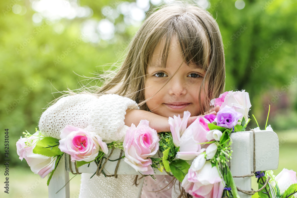 Fototapeta premium Cute kid girl posing with flowers outdoors
