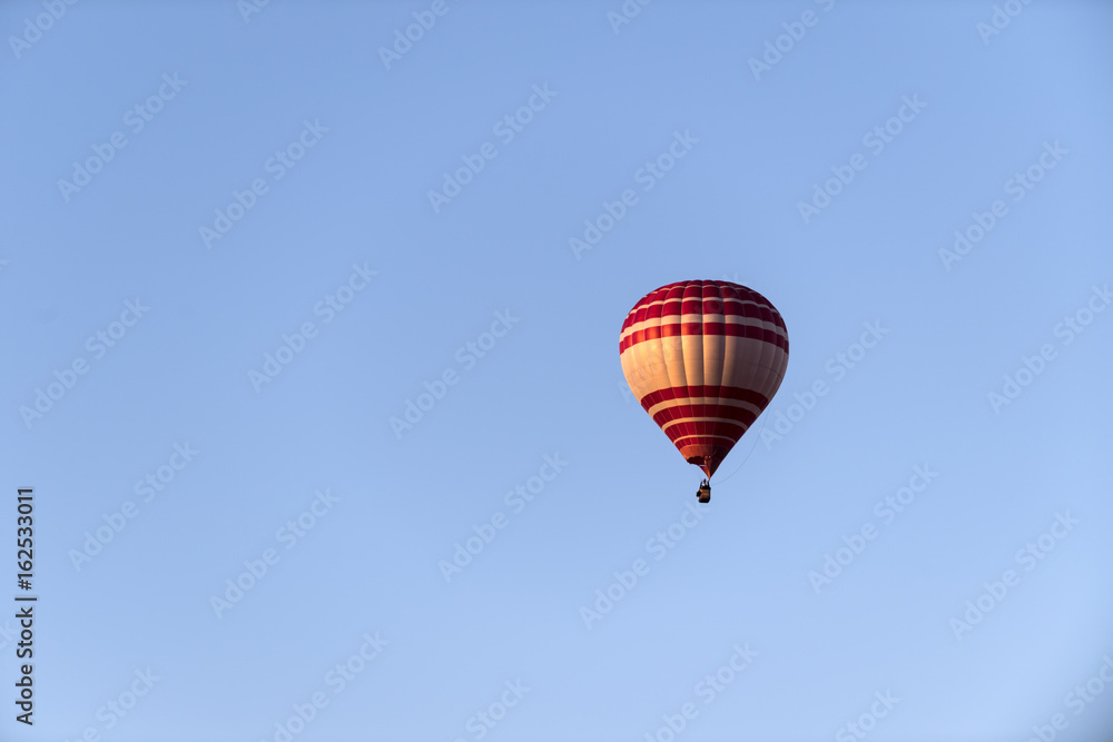 ein heißluftballon in rot und gelb vor blauem Himmel ein heißluftballon in rot und gelb vor blauem Himmel