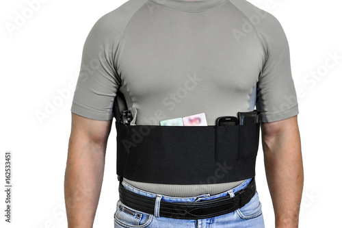Torso of a man dressed in civilian clothes, underneath the shirt there is a set for concealed carry weapons. Face hidden