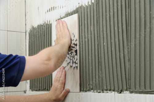 Tilers hands are  installing a ceramic tile. photo