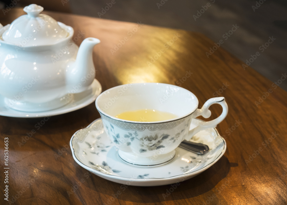 Antique Tea Set with White Jar and Beautiful Cup Full of Herbal Tea on Wooden Table for Tea Break Time or English Breakfast Antique Tea Set with White Jar and Beautiful Cup Full of Herbal Tea on Wooden Table for Tea Break Time or English Breakfast