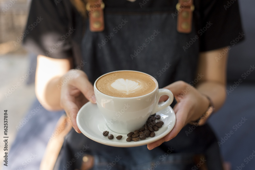 Barista is holding  latte art in hand