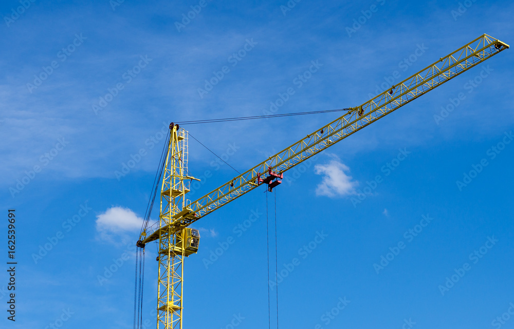 construction crane on the background of bright blue sky while working on a construction site
