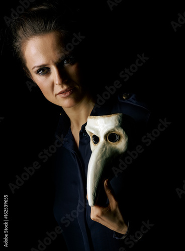 woman in dark dress isolated on black showing Venetian mask photo