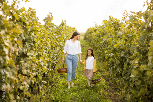 Young mother and her cute girl have fun in autumn vineyard