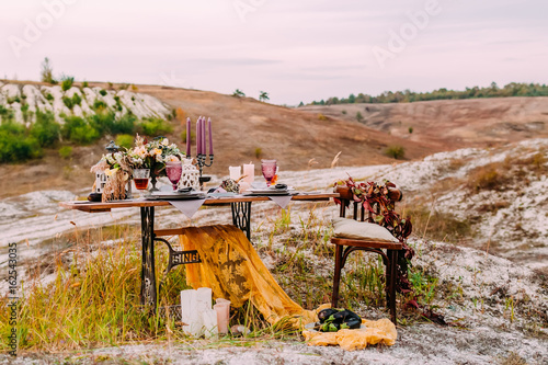 Wedding decorated table for two are standing on the open air in wedding ceremony area photo