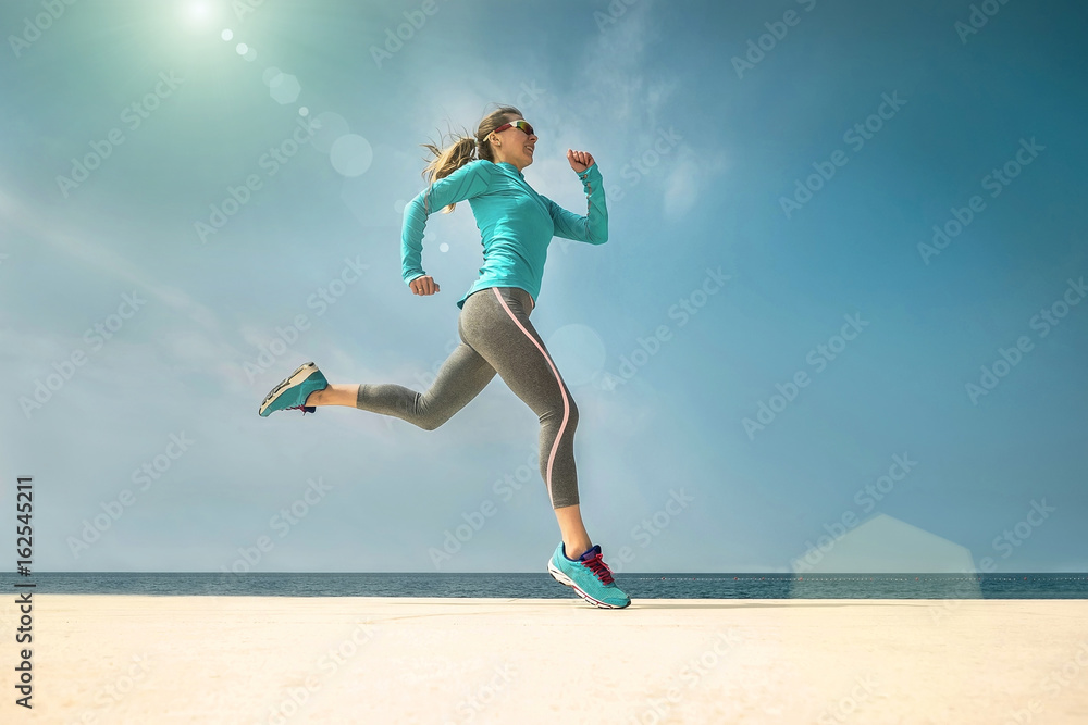 Woman running along the sealine coast under sunlight at sunny su Woman running along the sealine coast under sunlight at sunny su