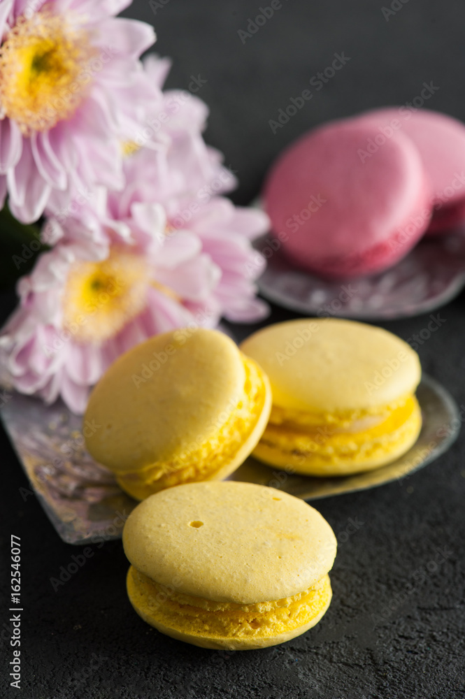 Closeup of yellow pink macaroons on black concrete Closeup of yellow pink macaroons on black concrete
