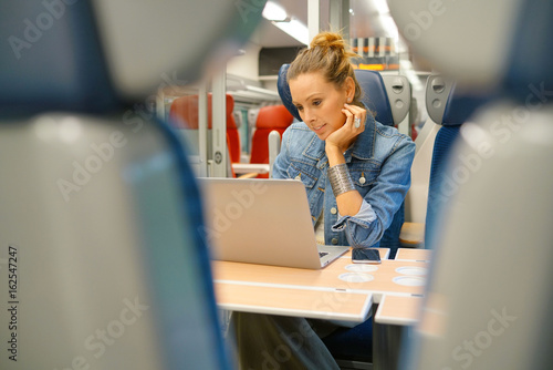 Young woman in train connected on laptop computer