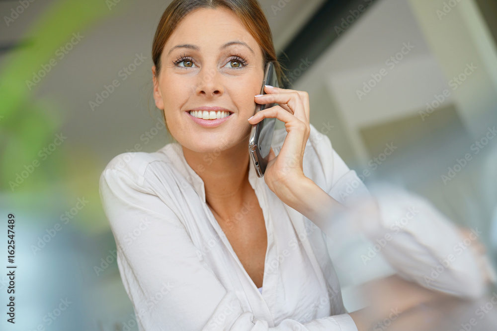 Woman sitting at desk talking on mobile phone Woman sitting at desk talking on mobile phone