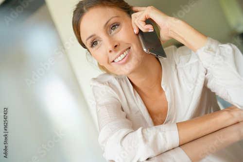 Woman sitting at desk talking on mobile phone