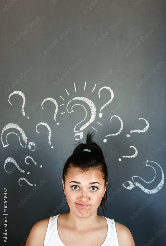 Young brunette girl with question marks on grey background Young brunette girl with question marks on grey background