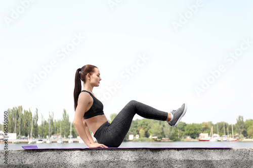 Pretty young woman doing exercises outdoors