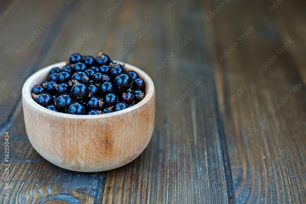 Useful berry. Black currants in a wooden bowl. The concept is healthy food, vitamins, diet and vegetarianism. Useful berry. Black currants in a wooden bowl. The concept is healthy food, vitamins, diet and vegetarianism.
