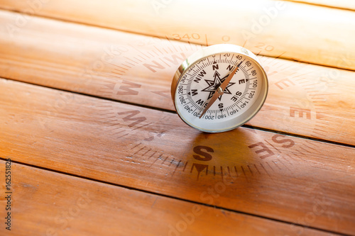 compass on wood table in sun light, find the right direction concept