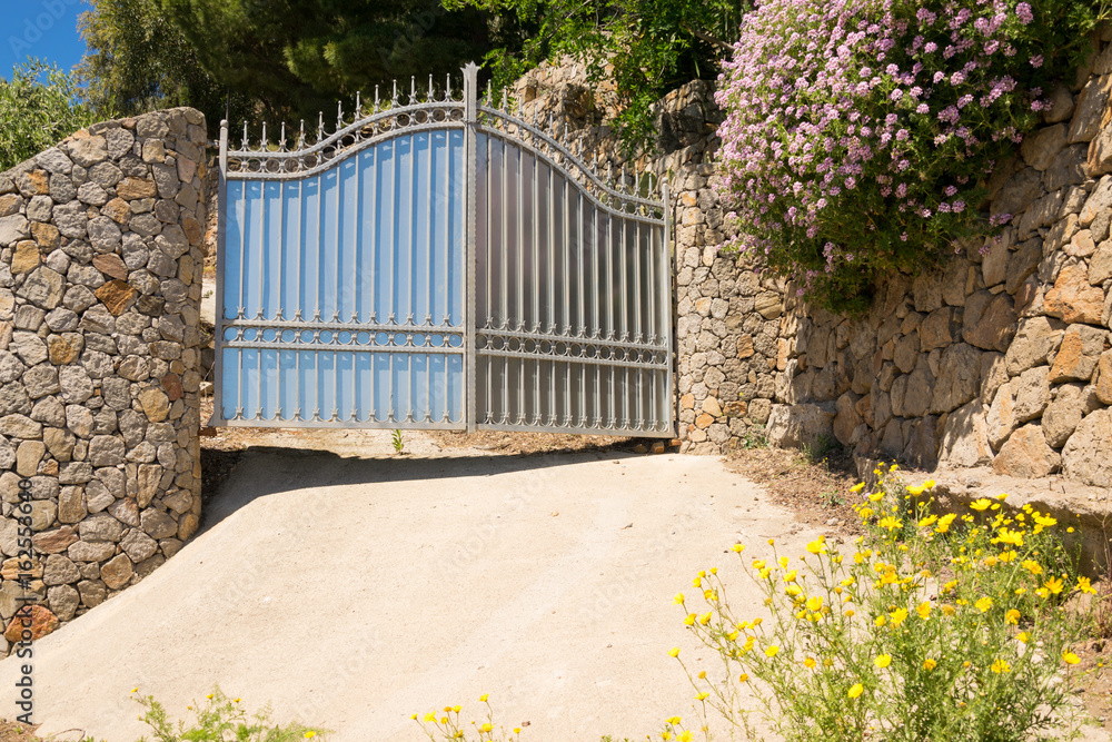 Fotografie Iron gateway placed in a beautiful stone wall