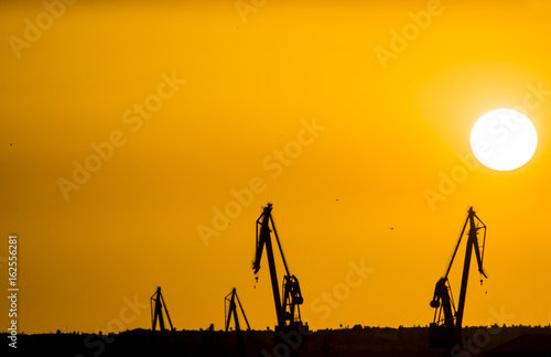 SEVILLE SPAIN - JUNE 25: Landscape of a cranes in a harbor at sunset with clouds on June 25 2017 in Seville, Andalusia, Spain.