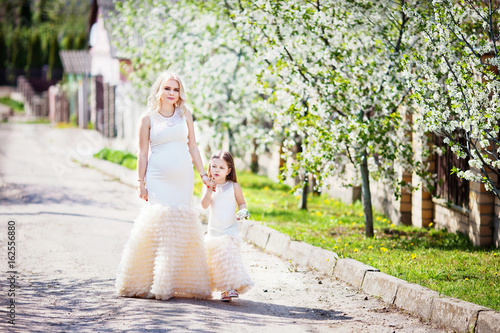 Pregnant mother and her small daughter in the summer gardenr. Family look portrait photo