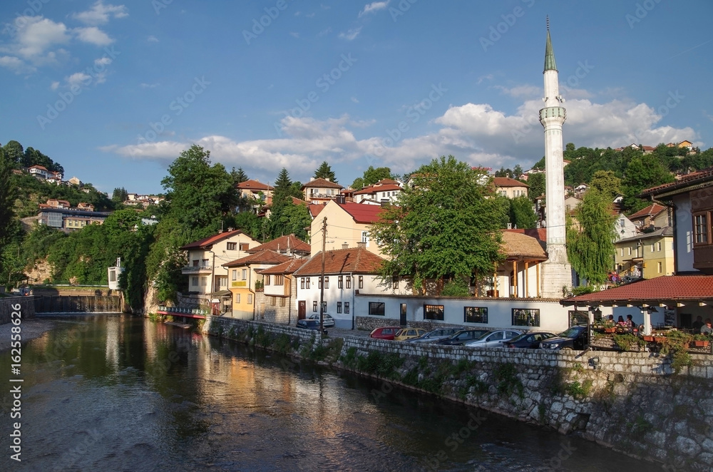 The city in beams of the evening sun. View of the Sarajevo with cloudy evening sky from the Miljacka River.  Bosnia and Herzegovina, Sarajevo