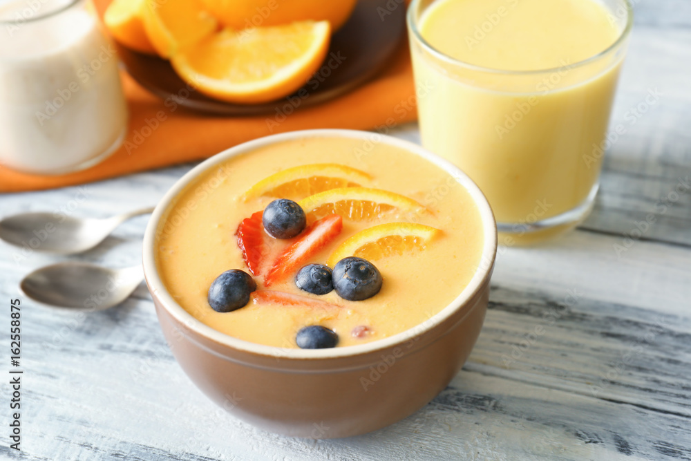 Bowl of fresh yogurt smoothie with orange and berries on wooden background Bowl of fresh yogurt smoothie with orange and berries on wooden background