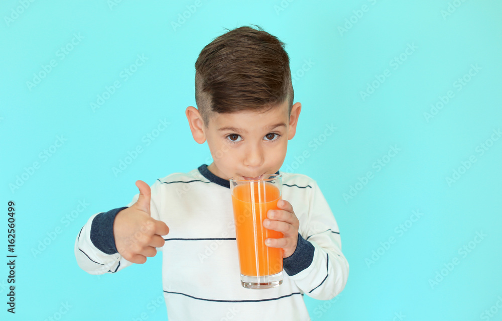 Cute little boy drinking juice on color background Cute little boy drinking juice on color background