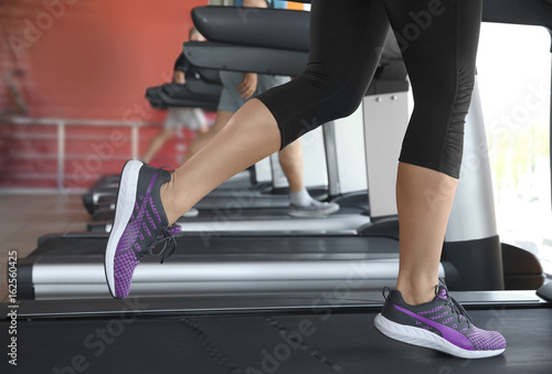 Sporty young woman training legs on treadmill in gym, closeup